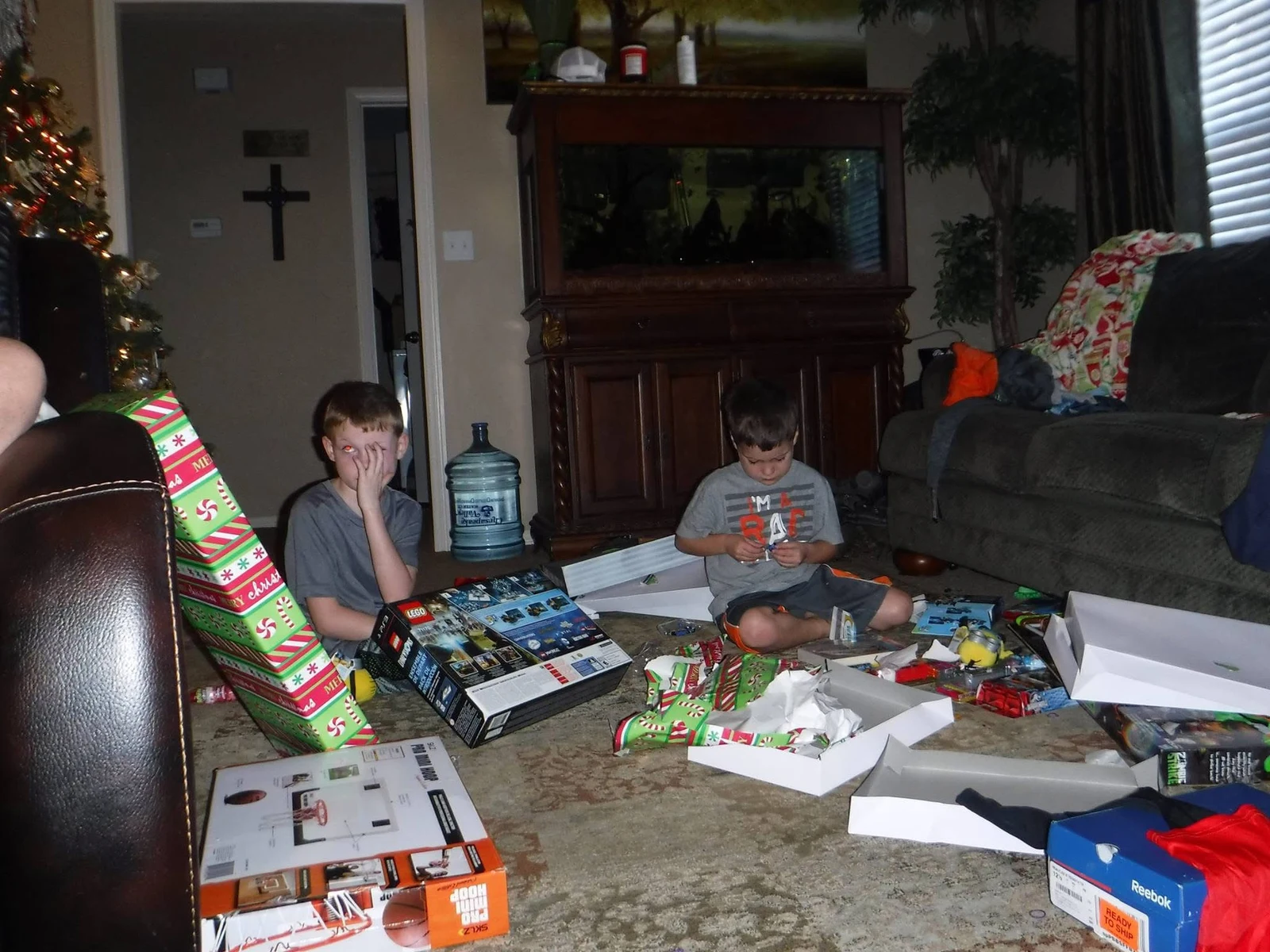 Two children surrounded by wrapping paper and LEGO boxes on Christmas morning.